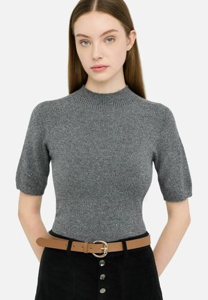 Top grigio a maniche corte in maglia con collo alto e dettagli di luccichio sottili, abbinato a una cintura color tan con fibbia circolare su una gonna nera.