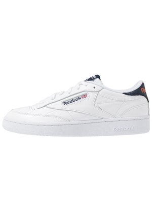 Sneaker in pelle bianca Reebok con chiusura stringata, linguetta sul tallone blu navy e logo Reebok con bandiera britannica sul lato e nella suola intermedia.