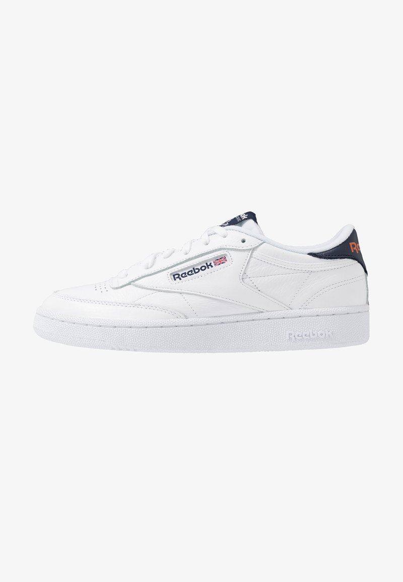 Baskets en cuir blanc Reebok avec fermeture à lacets, languette de talon bleu marine et logo Reebok avec drapeau britannique sur le côté et la semelle intermédiaire.