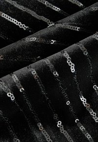 Black fabric with vertical rows of sewn-on silver sequins, featuring a textured weave and a slight sheen.