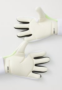 Gants de gardien de but avec des paumes en latex blanc, des accents noirs sur les doigts et un dos texturé vert. Ces gants offrent un ajustement confortable avec des coutures renforcées.