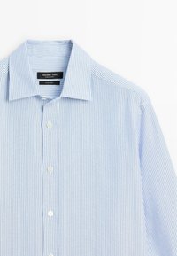 Camicia a righe blu chiaro realizzata in tessuto morbido, con colletto classico e chiusure a bottoni, caratterizzata da sottili righe bianche verticali.