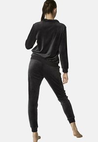 Zwart velours loungepak bestaande uit een long-sleeve top en tapse broek met elastische boorden, met een zachte textuur en een relaxte pasvorm.