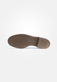 Suola di scarpa in gomma marrone con grip testurizzato, caratterizzata da un logo e un design curvo. Il bordo superiore è leggero e si trasforma in una forma piatta e arrotondata.