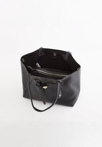 Zwarte leren tote bag met een gestructureerde afwerking, voorzien van twee handvatten, een binnenzak met rits en gouden hardware accenten.