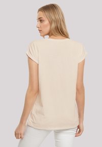 Beige short-sleeve t-shirt with rolled cuffs, made of soft fabric. Features a relaxed fit and rounded neckline, shown from the back.