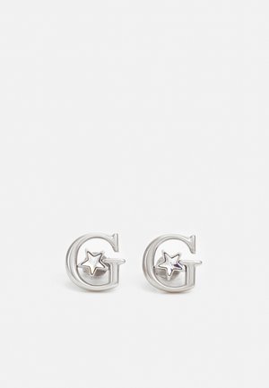Boucles d'oreilles en argent en forme de lettre G avec un petit détail en étoile à l'intérieur de chaque lettre sur fond blanc.