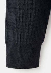 Schwarzer Strickpulloverärmel mit geripptem Bündchen, der vor einem schlichten hellen Hintergrund dargestellt ist.