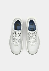 Light gray athletic shoes with a mesh upper, flat laces, and a blue insole featuring a black logo. Rounded toe and textured sole.
