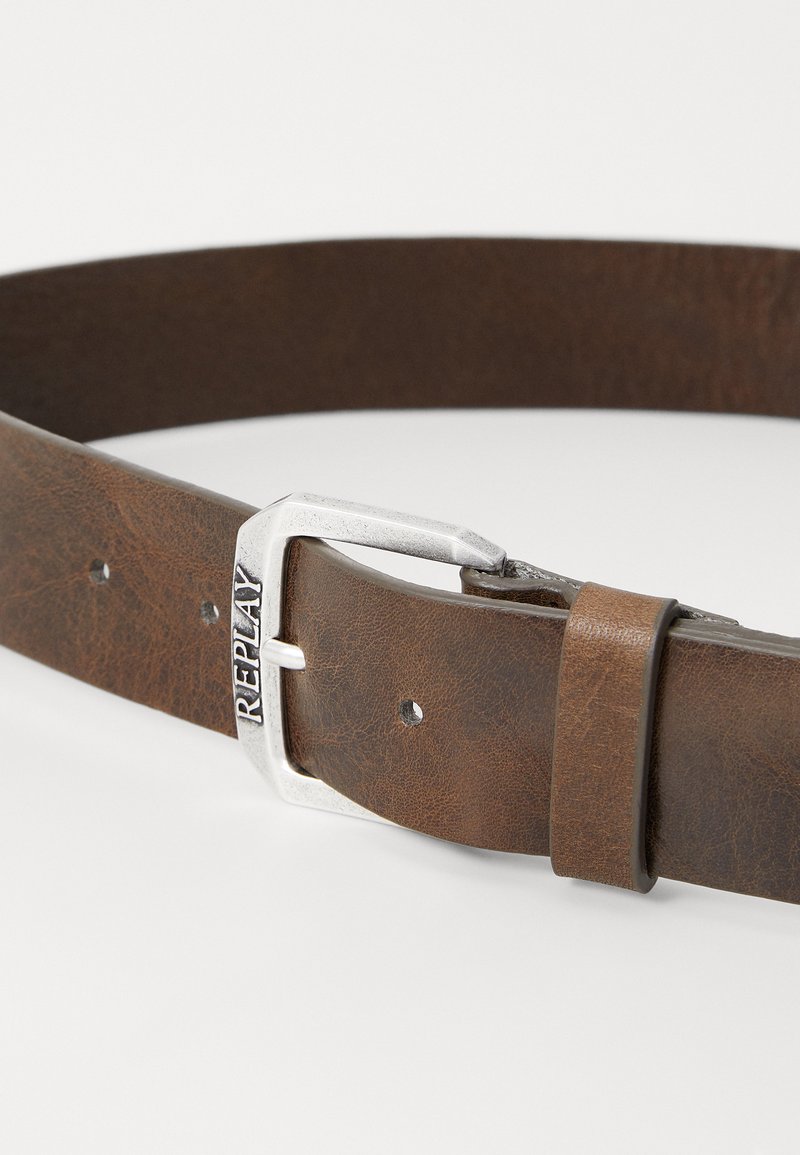 Cinturón de cuero marrón con una hebilla rectangular plateada grabada con la palabra "REPLAY." Presenta varios agujeros de ajuste y un acabado texturizado.