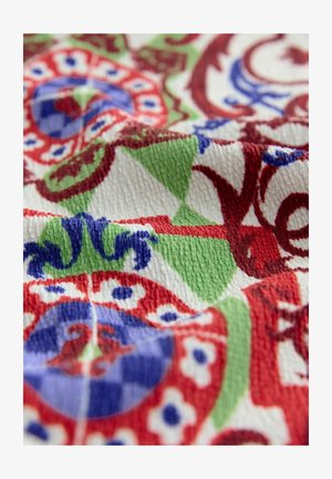 Tessuto tessile caratterizzato da motivi intricati in rosso, blu, verde e bianco; superficie texturizzata con un aspetto morbido e intrecciato.