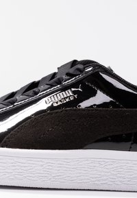 Sneaker Black Puma Basket con tomaia in pelle lucida, accenti in suede, lacci neri e suola in gomma bianca testurizzata.