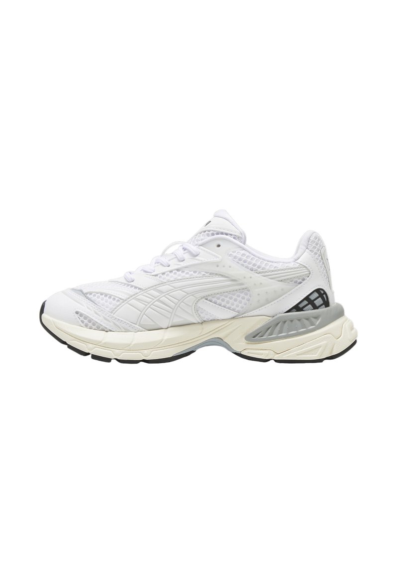 Weißer Sportschuh mit Obermaterial aus Mesh, strukturierten Details, gepolsterter Sohle und schwarzen Akzenten an der Ferse. Rundes Zehendesign.