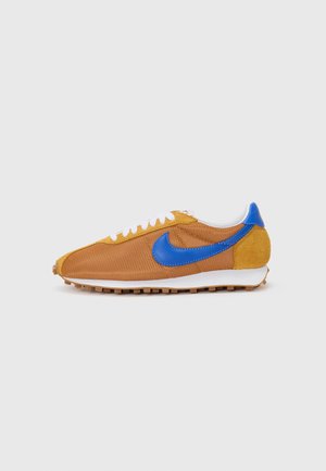 Žute smeđe tekstilne tenisice s plavim naglascima, bijelim vezicama i teksturiranom gumenom potplatom. Imaju prepoznatljiv plavi Nike swoosh logotip.