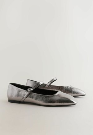 Ballerine metalliche argento con punta affusolata e una fascetta sul collo del piede, caratterizzate da un piccolo dettaglio con fibbia e suola piatta.