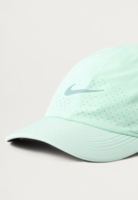 Minta zaļa Nike cepure ar mīkstu audumu, perforētiem izgriezumiem, izliekto brim un toņu swoosh logotipu sānos.