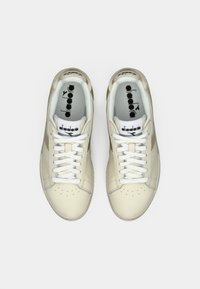 Pair of beige and white Diadora sneakers viewed from above on a white background, laced and clean with visible brand logos inside.