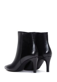 Botas de tobillo de cuero negro con una punta afilada y un tacón de aguja curvado. Superficie lisa sin patrones o acentos visibles.