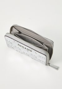Cartera plateada con un exterior texturizado, cierre de cremallera, múltiples compartimentos y un logo embosado brillante. Forro interior suave.