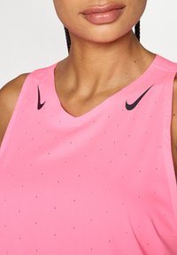 Pink Nike athletic tank top with a v-neck design, featuring small black perforations and a black logo on the left shoulder.