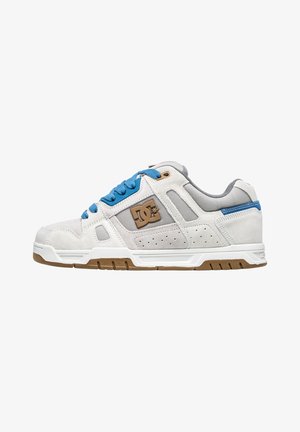 Biele a šedé semišové tenisky s modrými šnúrkami, hnedými akcentmi, perforovanými detailmi a textúrovanou podrážkou; na strane sa nachádza logo.