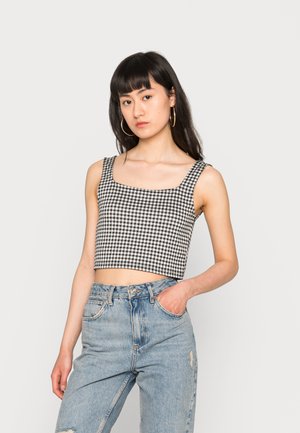 Top cropped em gingham preto e branco com decote quadrado e alças largas, feito de um tecido leve, combinado com jeans rasgados de cintura alta.
