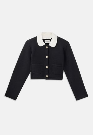 Chaqueta corta de color azul marino con un cuello blanco, botones dorados, dos bolsillos frontales y un acabado de tela texturizada.