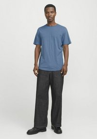 Blue short-sleeve t-shirt paired with dark, wide-leg jeans and black boots. The shirt has a round neckline and a smooth texture.