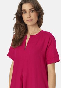 Fuchsia linnen blouse met korte mouwen, een lichte V-hals en een losse fit. Beschikt over een voorpanneel en een zachte, gestructureerde stof.
