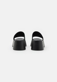 Svarte plattform sandaler med glatt tekstur, åpen bakdel og bred, avrundet hældesign. Minimalistisk stil uten synlig merkevare.