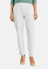 Witte broek met een geplooid front en opgerolde mouwen, gemaakt van lichtgewicht stof. Gecombineerd met neutrale hoge hakken.