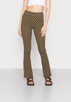 Calças largas castanhas com um padrão geometricamente repetido em amarelo. Tecido suave com um cós elástico e corte até ao tornozelo.