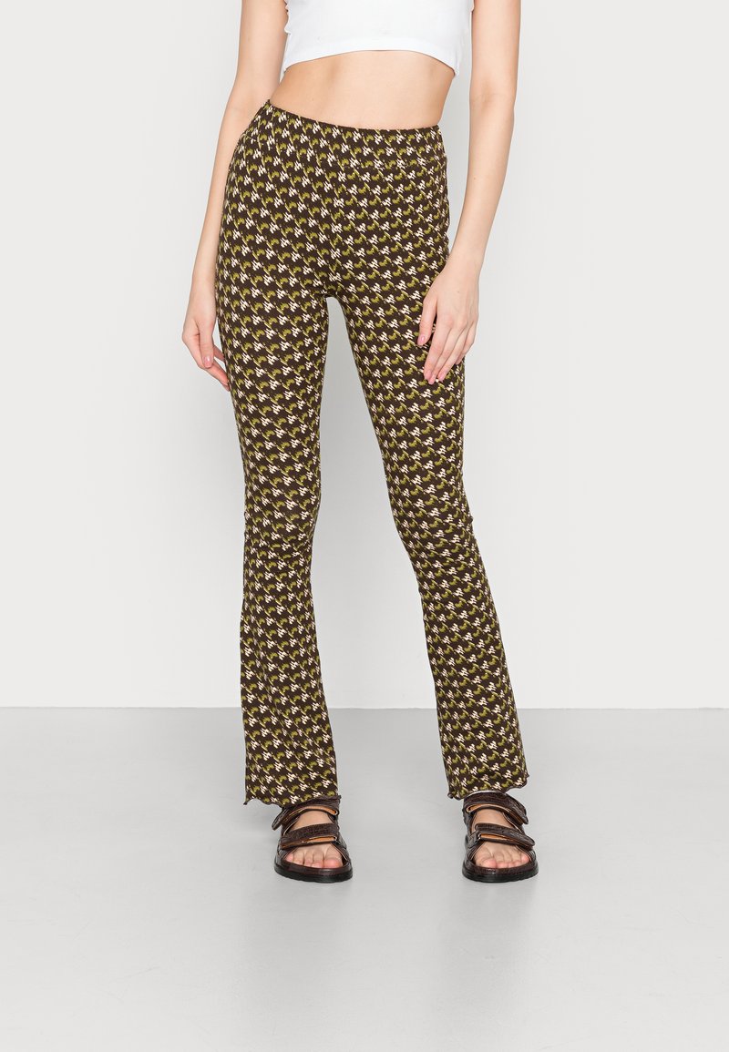 Calças largas castanhas com um padrão geometricamente repetido em amarelo. Tecido suave com um cós elástico e corte até ao tornozelo.