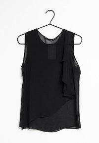 Haut noir sans manches en tissu transparent, avec des volants drapés sur un côté et un ourlet arrondi, présenté sur un cintre noir.