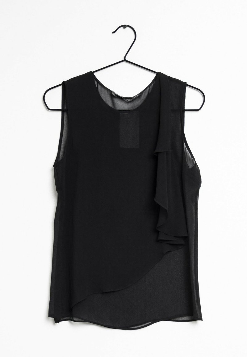 Haut noir sans manches en tissu transparent, avec des volants drapés sur un côté et un ourlet arrondi, présenté sur un cintre noir.