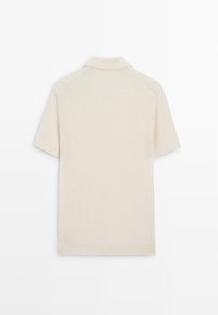 Polo beige à manches courtes en maille côtelée, vu de dos avec un col plié sur fond blanc.