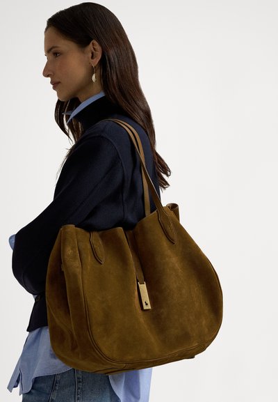 Smeđa torba od brušene kože s dvije čvrste drške, glatkom kožnom oznakom i mekim, zaobljenim oblikom. Ima minimalistički dizajn i bogatu teksturu.