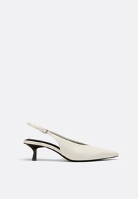 Chaussure escarpin à talon kitten en cuir blanc cassé avec bout pointu et bride réglable à boucle sur fond neutre.