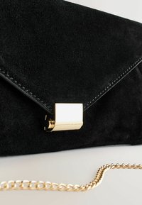 Black suede clutch with a gold metallic clasp, featuring a fold-over flap design and a gold chain strap. Smooth texture and no visible patterns.