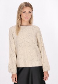 Sweter w kolorze kremowym, wydziergany, o luźnym kroju, z czarnymi akcentami, prążkowanymi mankietami i okrągłym dekoltem.