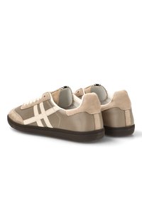 Zapatillas beige con una mezcla de materiales de ante y malla, que presentan un diseño de rayas en color crema y una suela de goma oscura.