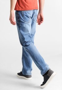 Ljusblå denimjeans med rak benmodell, med bakfickor och en blekt tvätt. Kombinerat med svarta och grå sneakers.