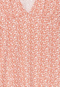 Robe florale en tissu orange doux, ornée d'un motif blanc de petites fleurs, avec un décolleté en V et des détails froncés pour la texture.