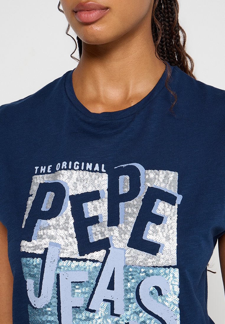 Camiseta azul marino con un gráfico decorado con lentejuelas que dice "THE ORIGINAL PEPE JEANS". De manga corta, fabricada en tejido suave y con escote redondo.