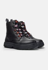 Botas de tobillo de cuero negro con bordados florales coloridos en los cordones, punta redonda y suela de goma gruesa para una mejor tracción.