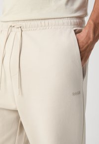 BOSS HADIKO - Spodnji deli trenirk - light beige