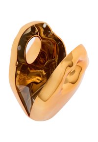 Glinsende gulds skulptur med organisk form, glat overflade og små cirkulære udskæringer. Reflekterende overflade fremhæver de flydende konturer.