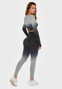 Grå gradient atletisk sæt bestående af en tætsiddende langærmet crop top og højtaljede leggings med teksturerede detaljer og flade sømme.
