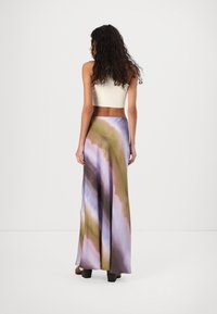 Hosszú, lebegő szoknya, amely több színben tye-dye mintákkal rendelkezik, lilás, zöld és bézs árnyalatokban. Könnyű anyagból készült, sima tapintású.