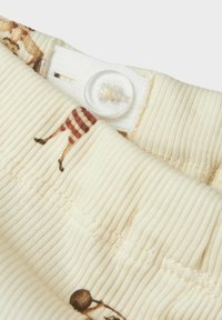 Off-white ribbat tyg med justerbar midjeband och elastiskt, med delvis brunrandig djurtryck.